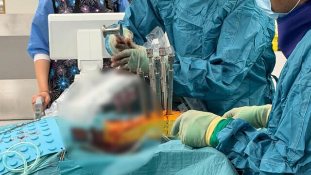 Surgeon inserting pedicle screws during spinal fixation surgery Surgeon inserting pedicle screws during spinal fixation surgery