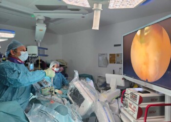 Operating room setup for endoscopic spine surgery with surgical team and imaging equipment